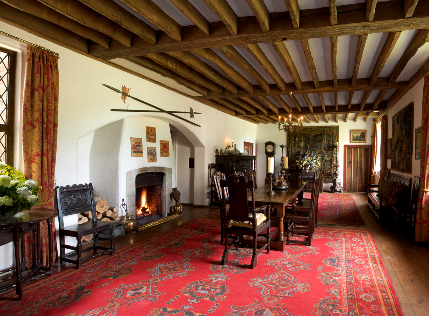 Historical dining room with fireplace and wooden beams.