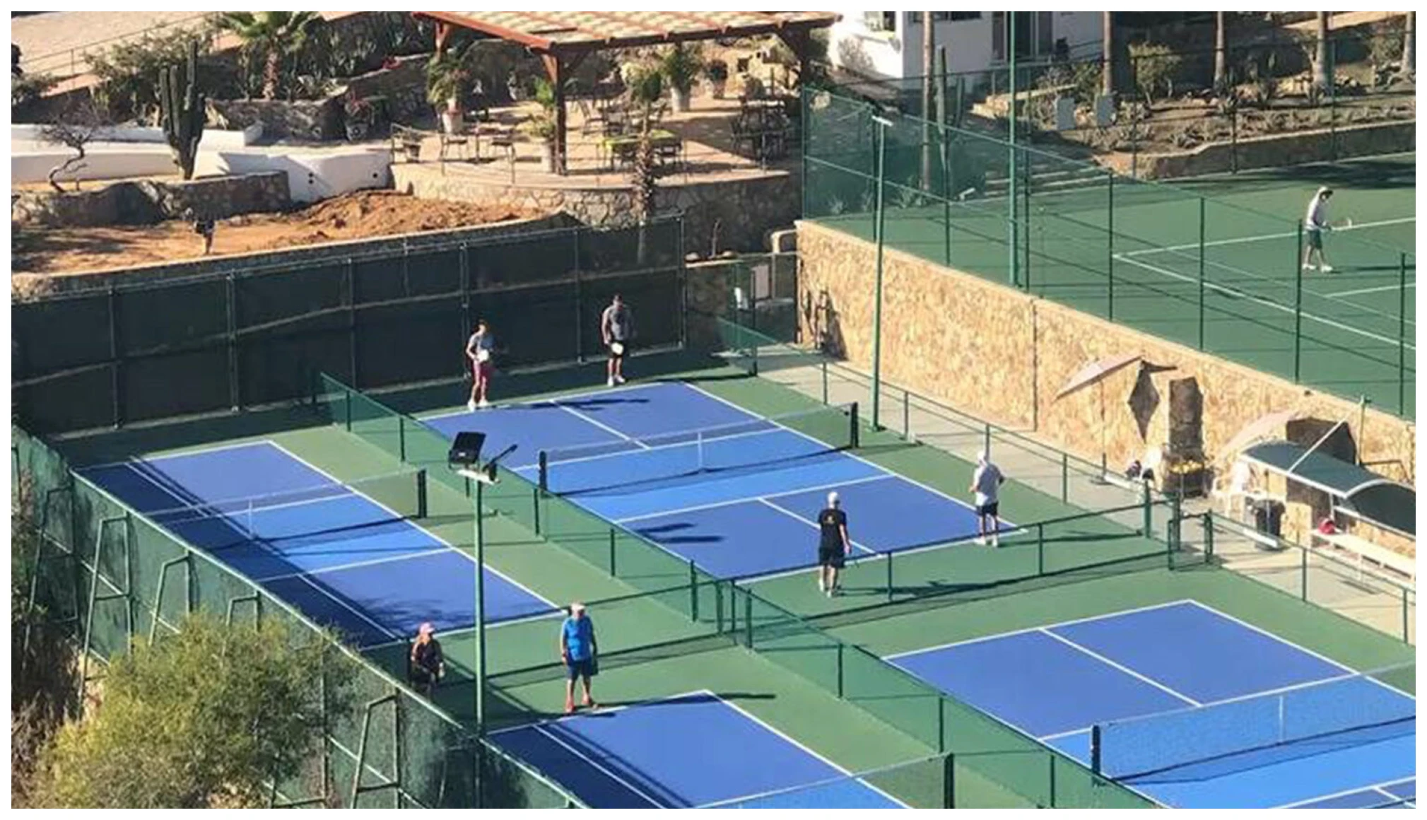 People playing on outdoor tennis courts.