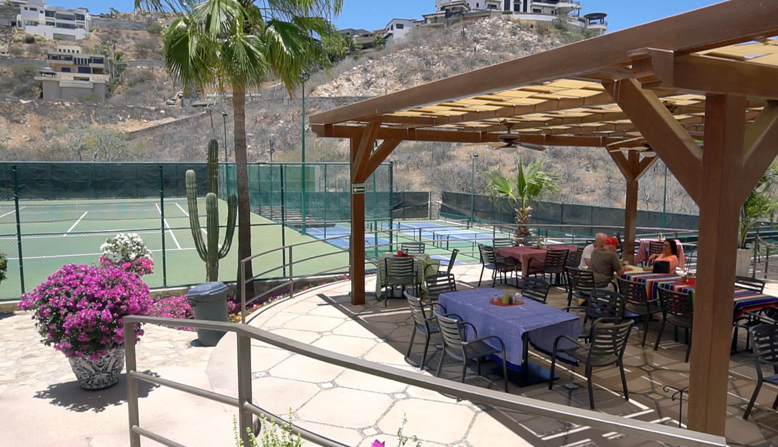 Shaded patio dining beside tennis court and cactus